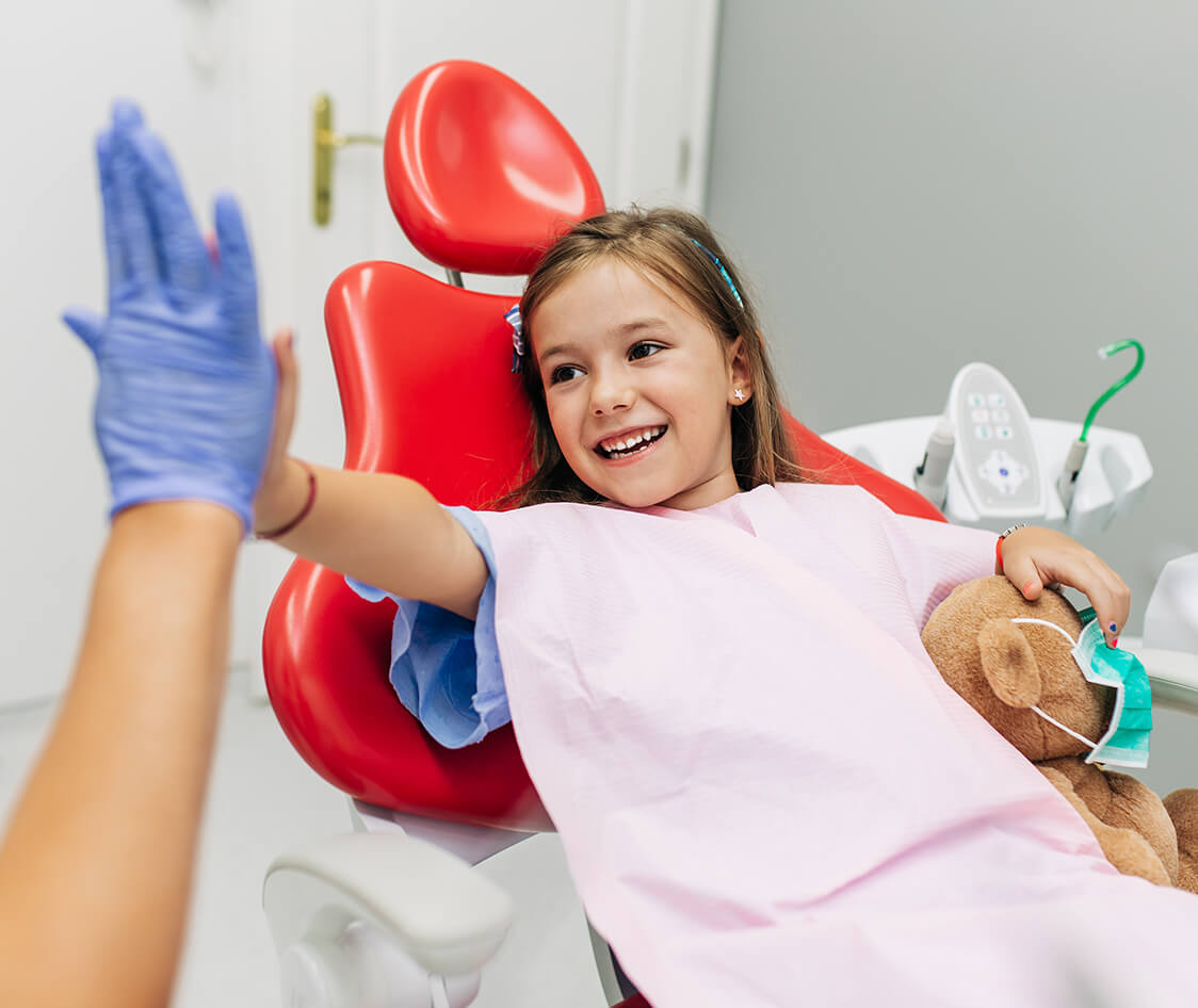 Cute little girl sitting on dental chair and having dental treatment.