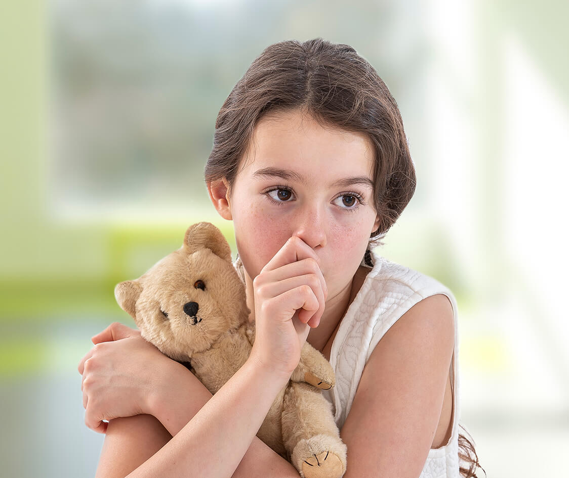 Teen girl lovingly holding a teddy bear sucking her thumb